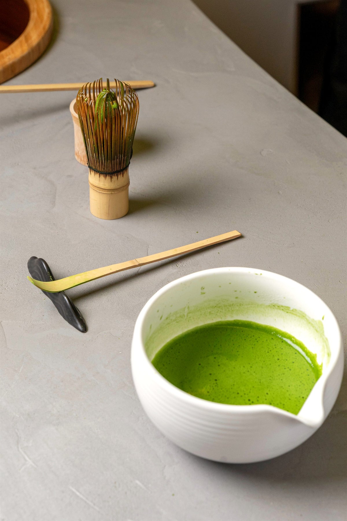 Bamboo chasen and chashaku next to a bowl of freshly whisked matcha