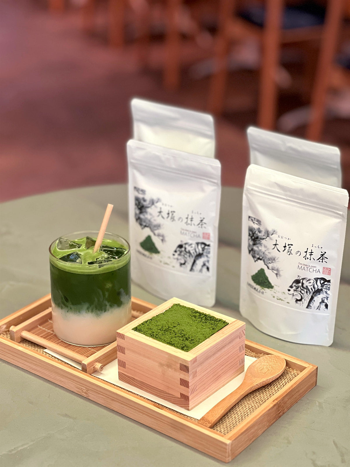 Otsuka Seicha matcha bags with an iced matcha latte and matcha tiramisu in a hinoki masu box