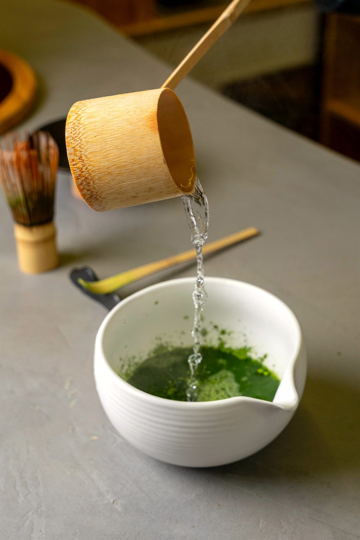 Pouring hot water over Shizuoka matcha in a white bowl to make usucha