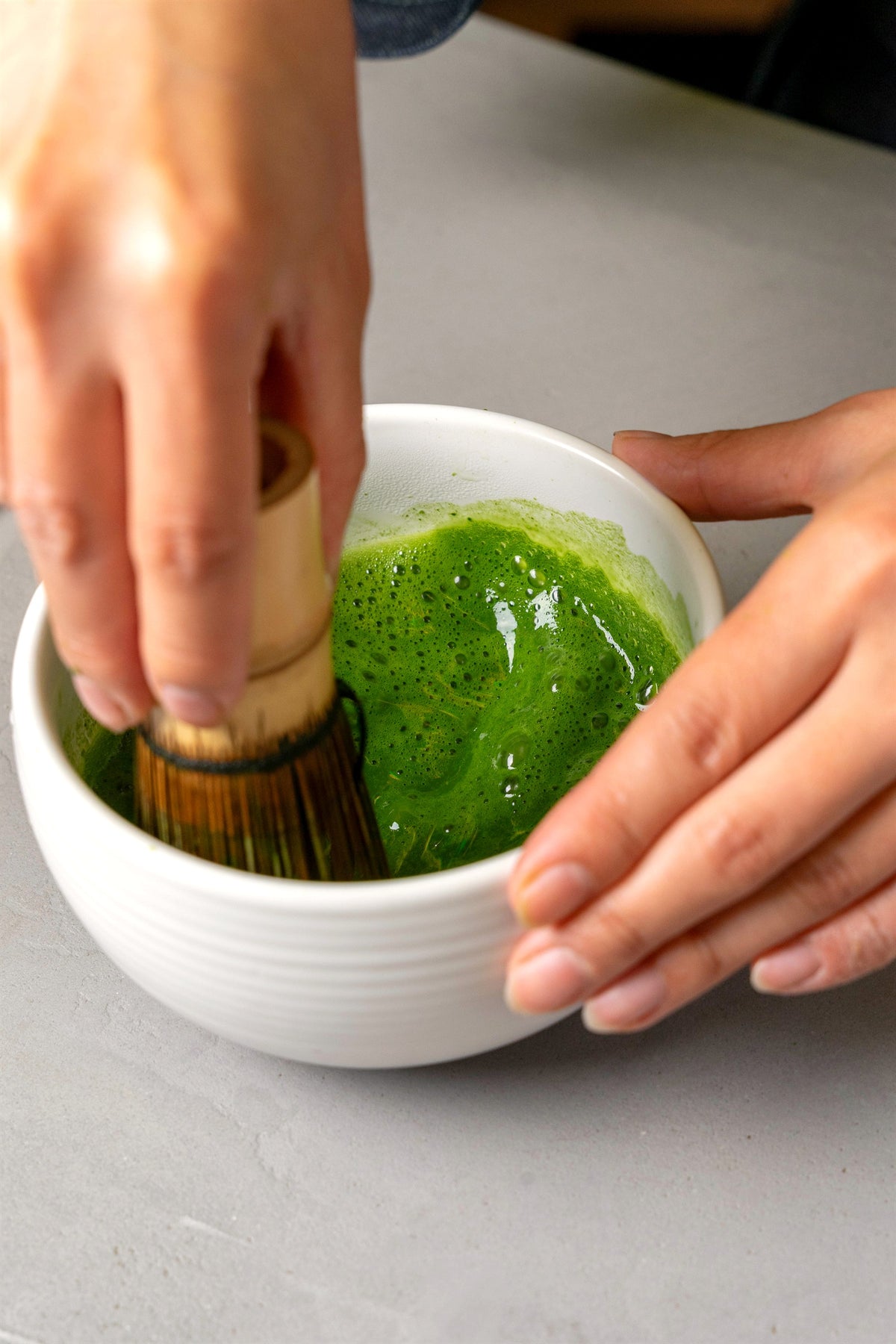 Saki whisking matcha with a bamboo chasen until it foams